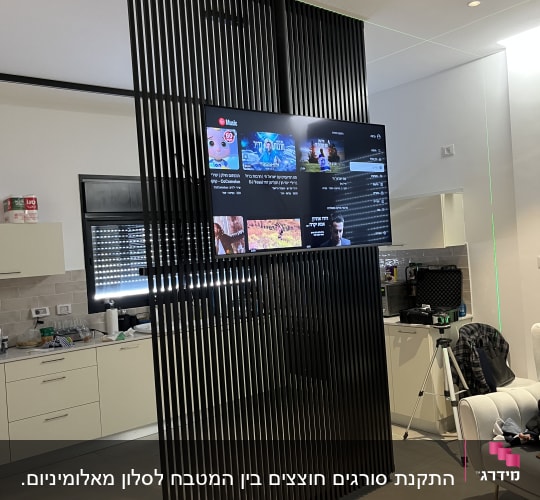 מסך טלוויזיה תלוי על מחיצה עם קורות שחורות